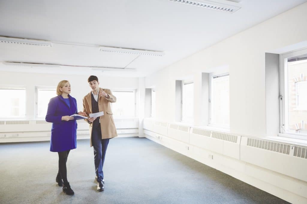 Un asesor inmobiliario muestra a una señora un local comercial vacío para alquiler o venta.