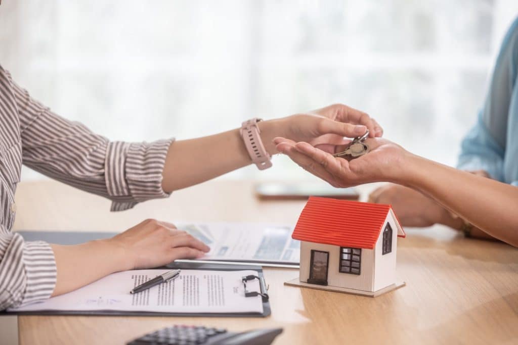 Una asesora inmobiliaria entrega las llaves de la nueva vivienda al comprador.