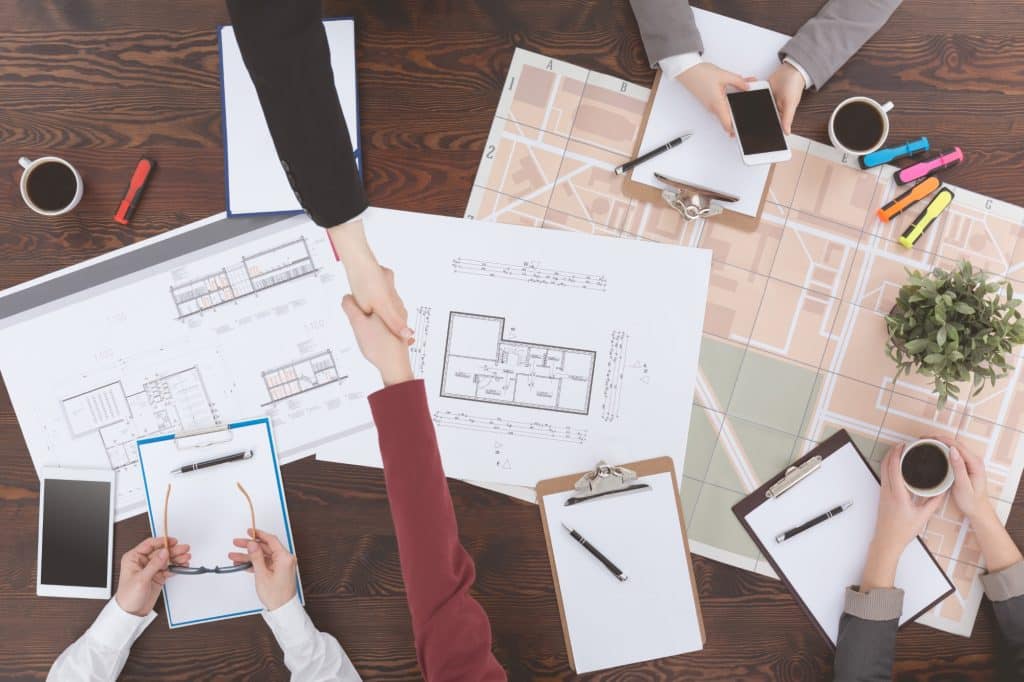 Equipo de asesores inmobiliarios trabajando sobre el plano de unas viviendas.