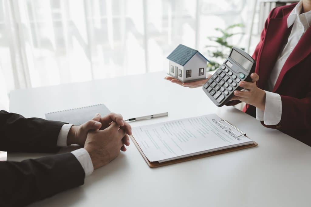 Asesor hipotecario enseña cifras de la operación de compraventa con una calculadora al cliente
